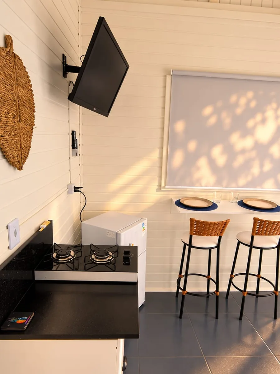 Cozinha do loft com cooktop, frigobar e Smart TV